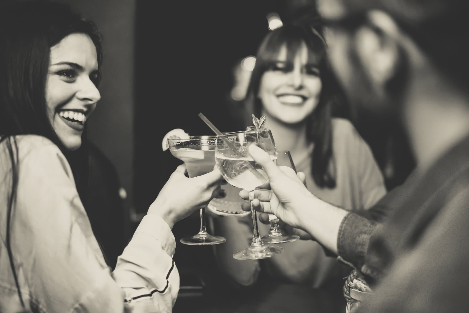 Friends smiling and raising glasses at bar